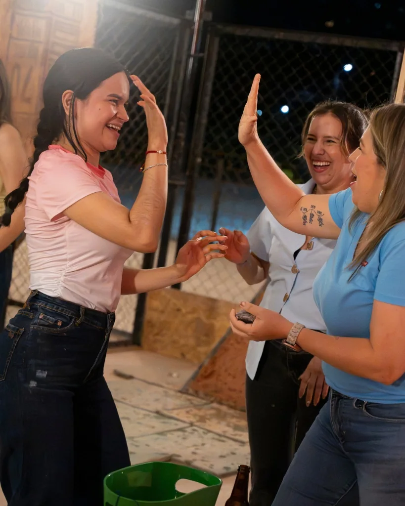 Grupo de amigas celebrando y jugando tejo con picadas criollas y cerveza helada en Tejodiste